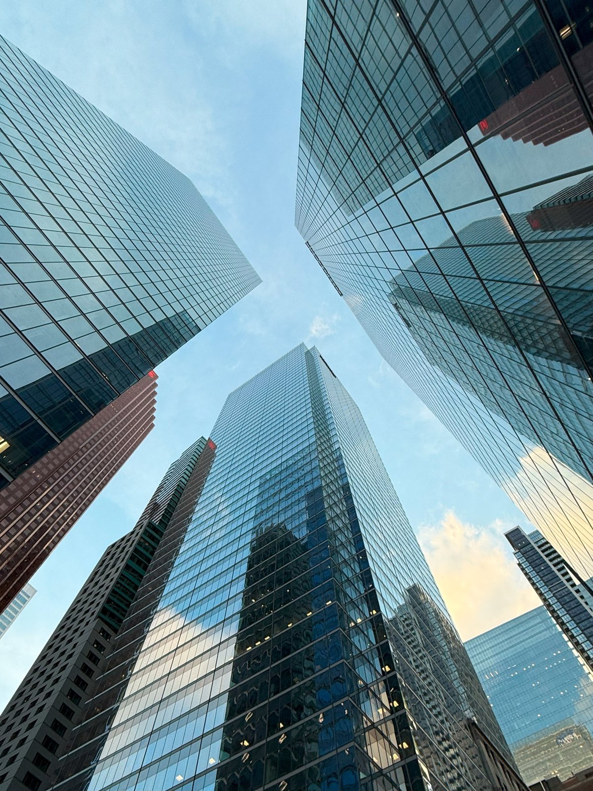 Modern glass skyscrapers reflecting the sky in business district — MAY Engineering commercial engineering Ontario
