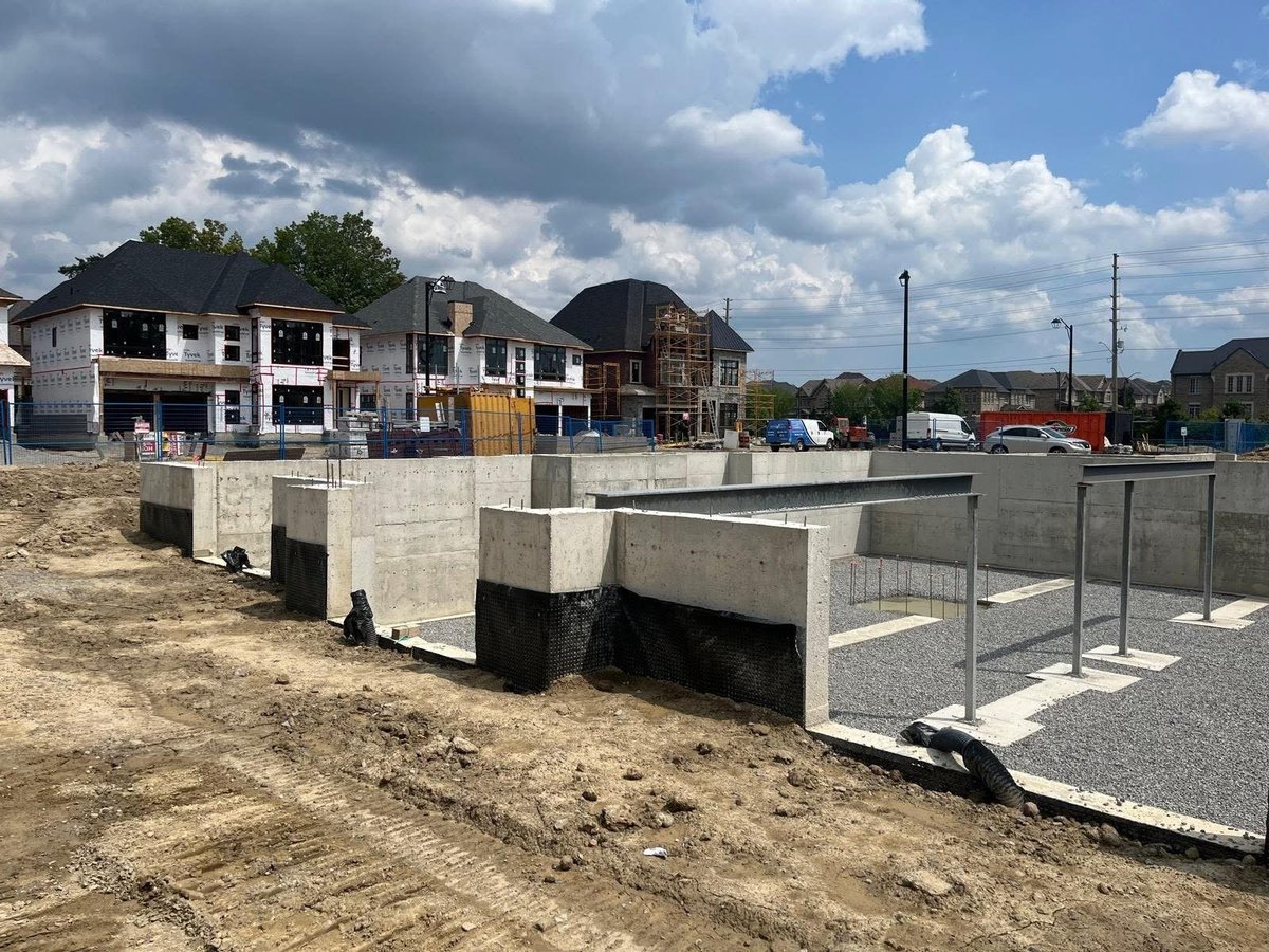 Construction site with concrete foundation blocks and partially built houses — structural engineering industrial warehouse project in Hamilton Ontario — MAY Engineering Inc.