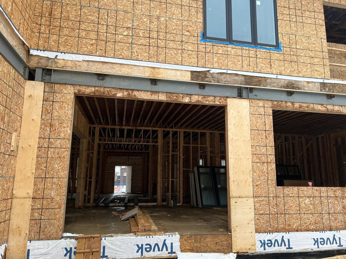 Unfinished brick building under construction with exposed wooden framing and open storefront entrance — MAY Engineering shop drawings Ontario